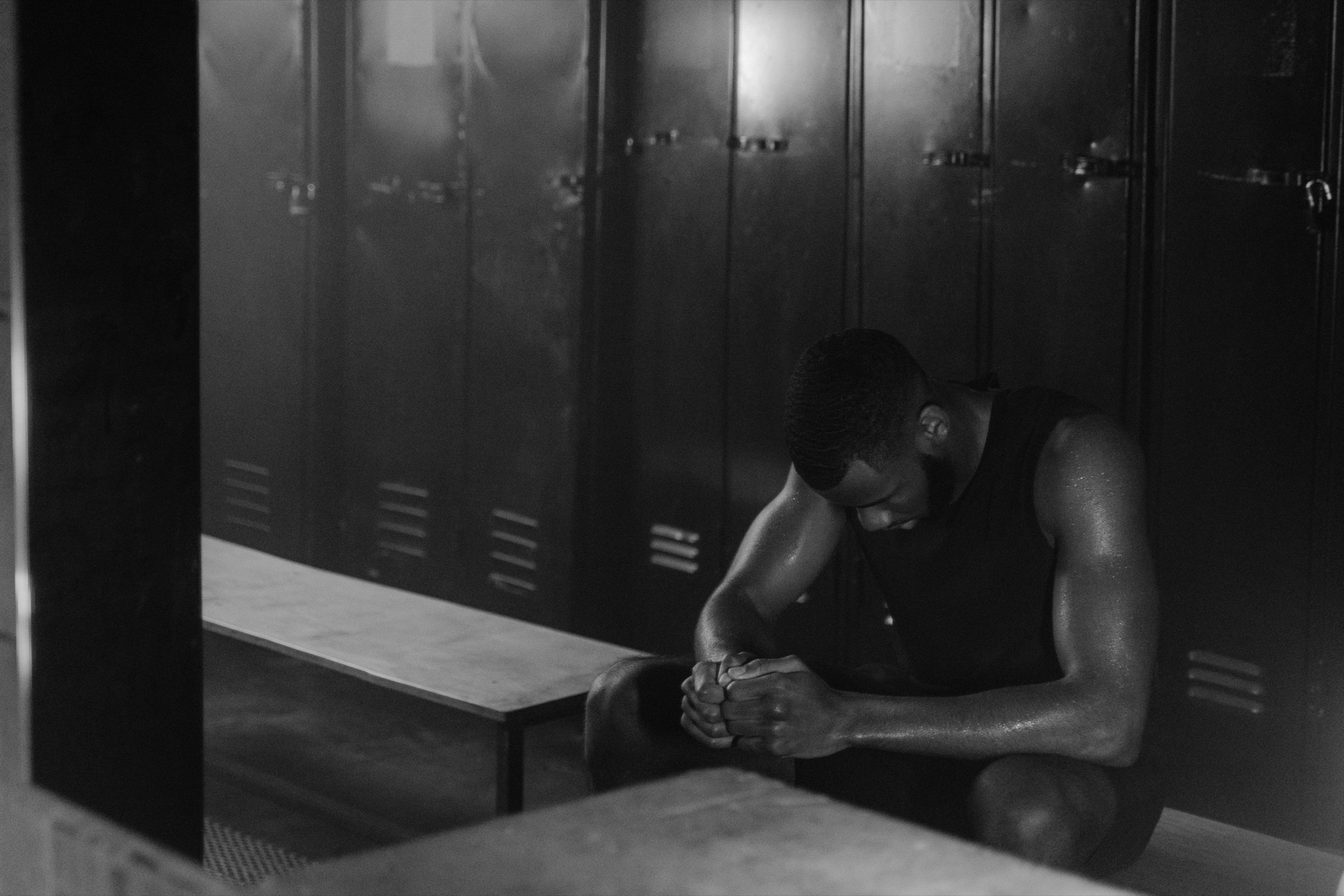 An athlete reflecting alone on a locker-room bench after training